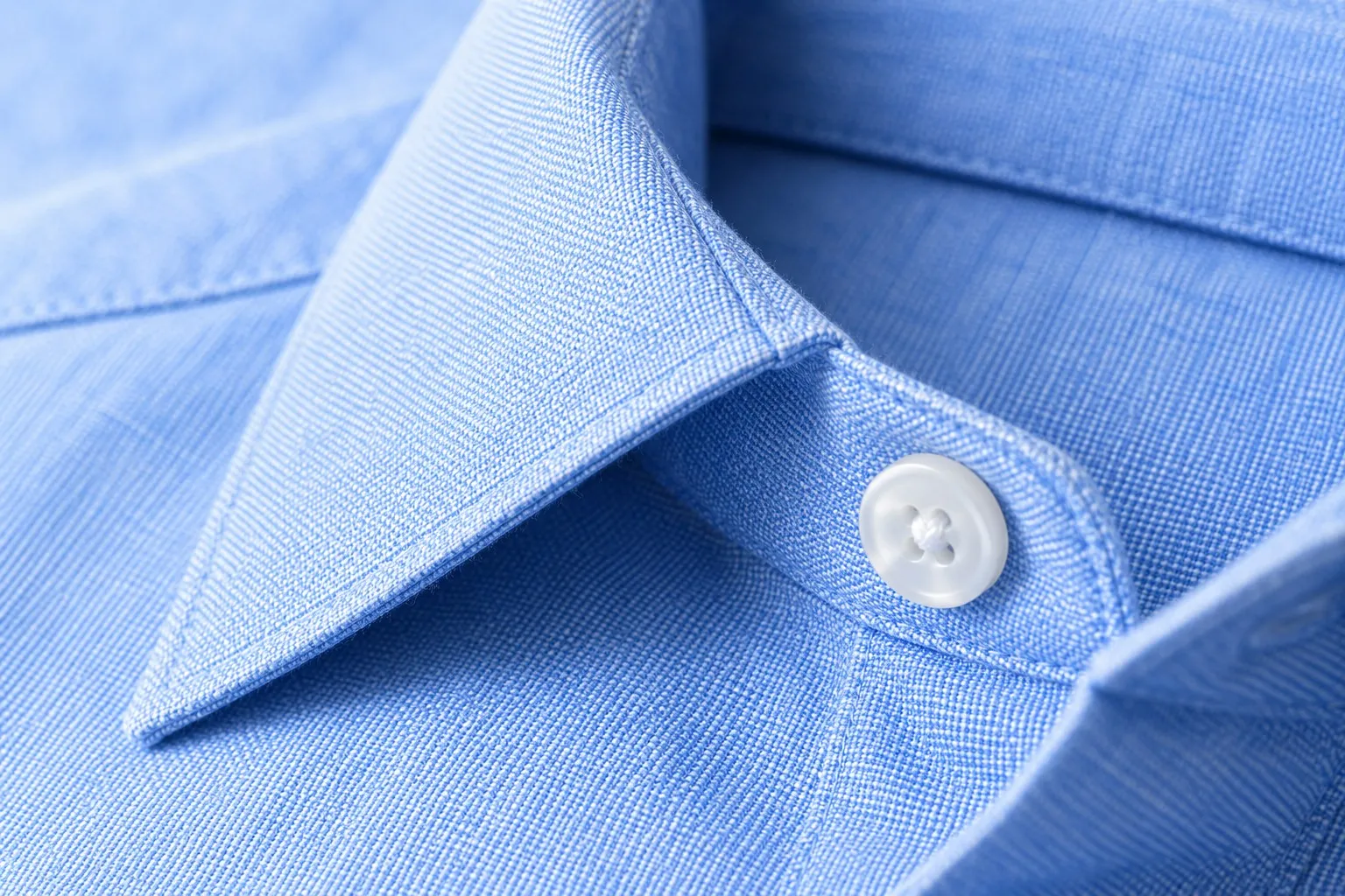 Close-up of a pressed light-blue shirt collar and button